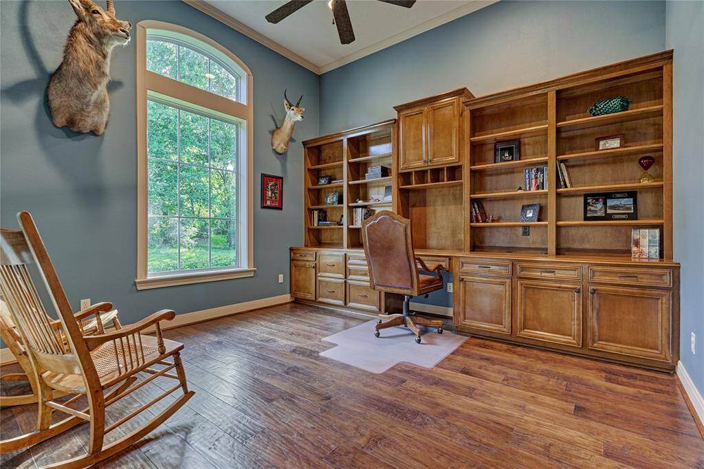 The handsome study boasts of rich wood flooring, a soaring ceiling with crown molding and a wall of built in cabinetry.