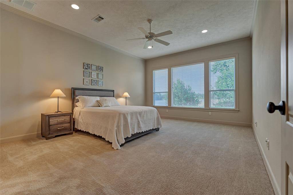 The private primary retreat features crown molding, plush carpeting and gorgeous views of the lake.