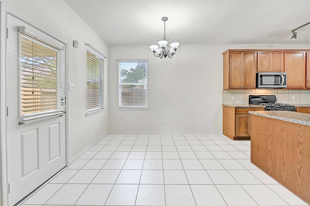 The breakfast table area is light and bright with two windows and a door to access the covered back patio.