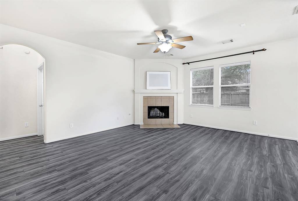 Spacious living room with updated flooring, cozy fireplace, and large windows.