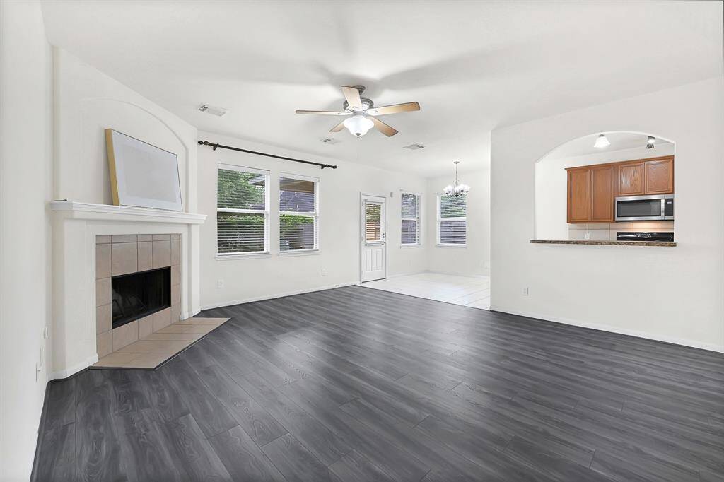 Spacious living room with updated flooring, cozy fireplace, and large windows.