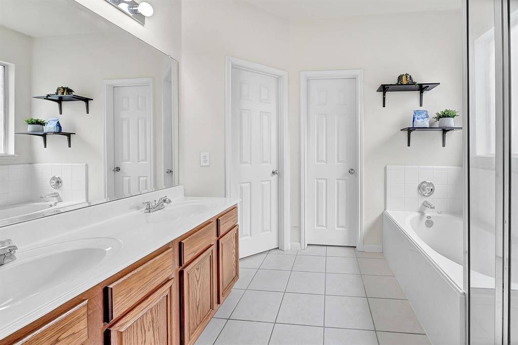 The primary bathroom features a double vanity, large mirror, and shelving for decor or storage.