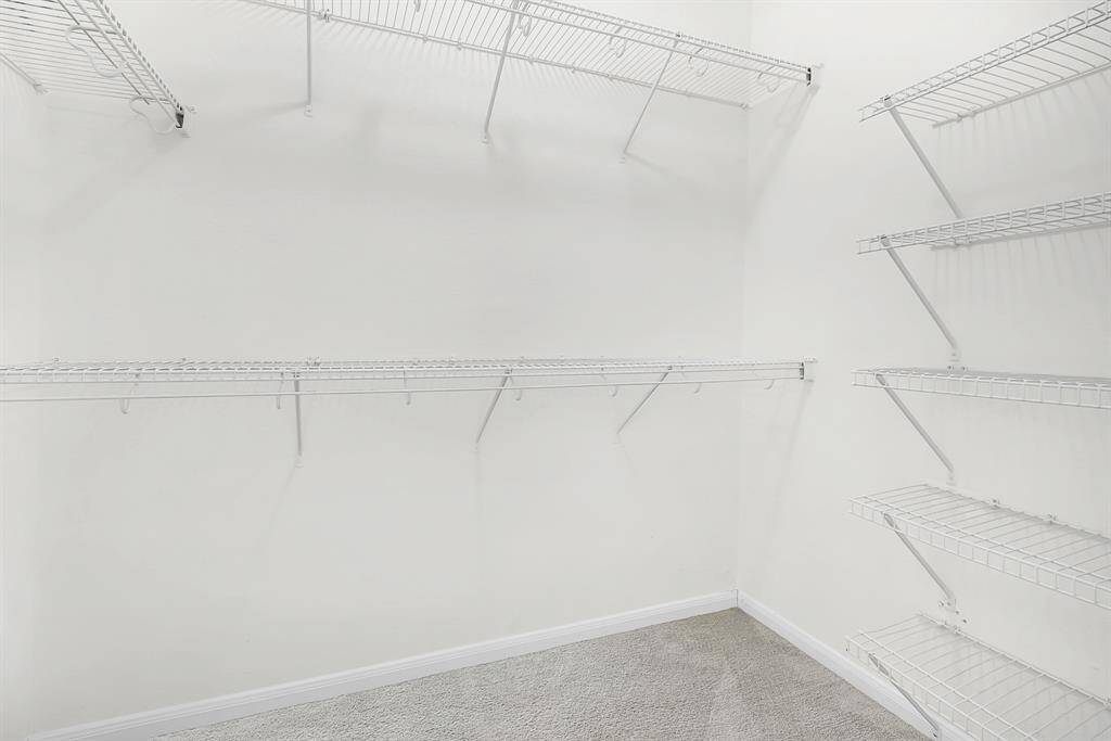 Primary closet with multiple hanging rods and shelves for storage.