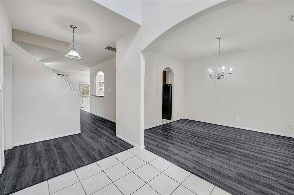 Upon entering the front door, guests get a feel for the open-concept floor plan with views of the entry, formal dining, and living rooms. To the right, the architectural arch sets this dining room apart. Note the NEW laminate wood flooring (2025)!