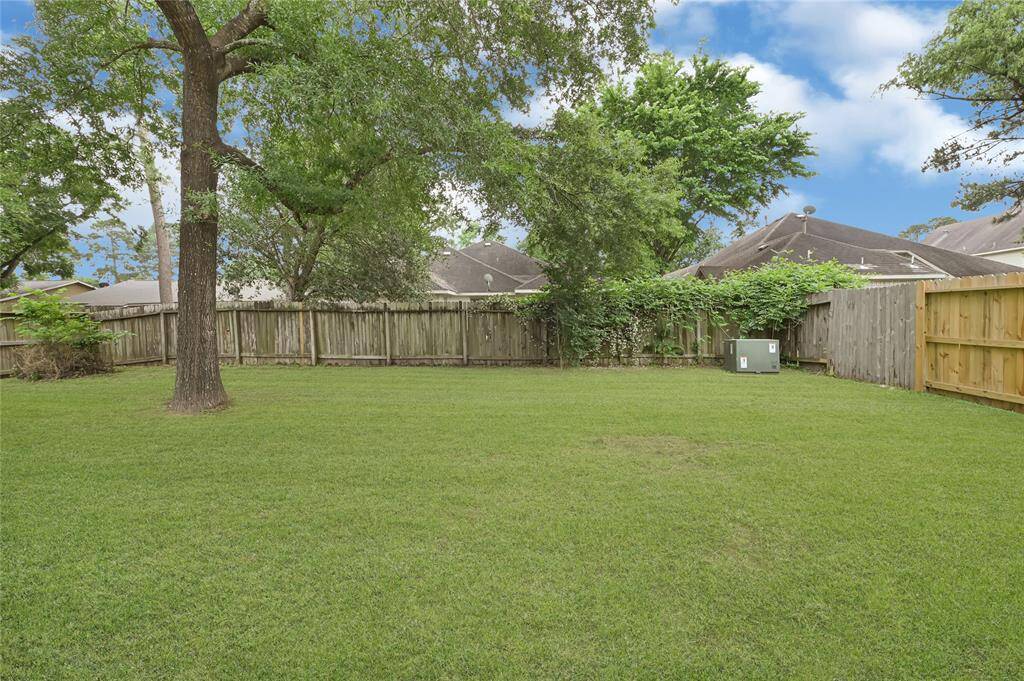 Large backyard with mature tree and wooden fence. *Grass edited*