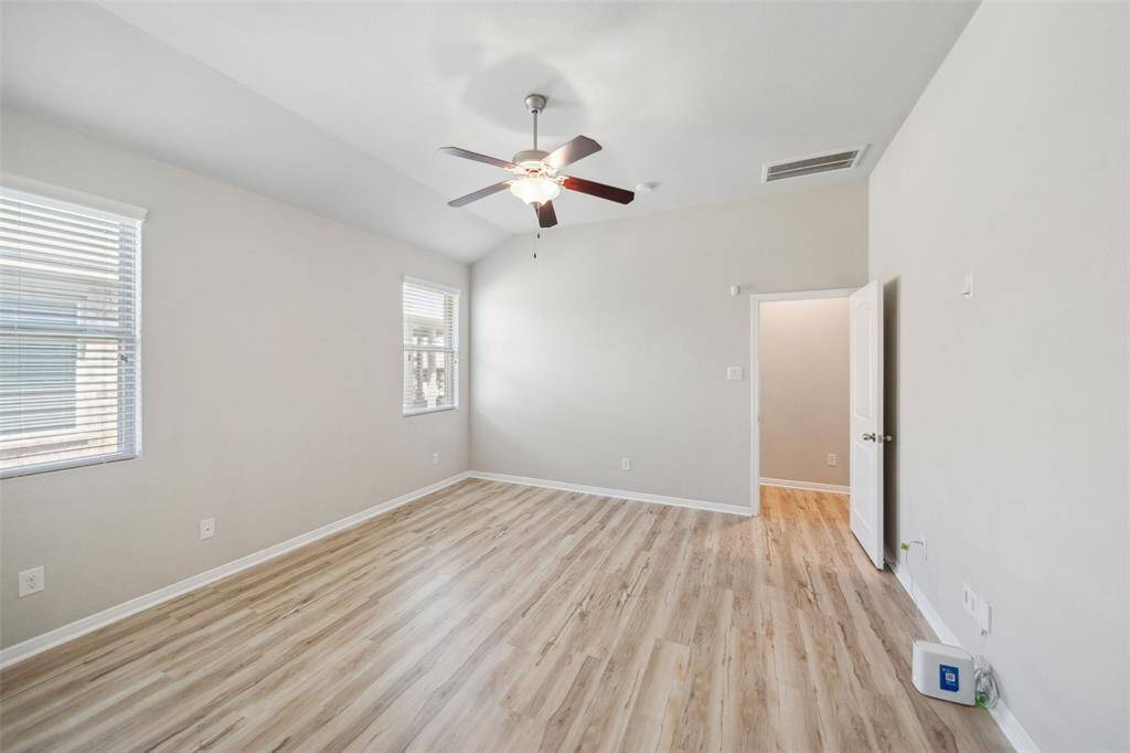 Luxurious primary suite filled with natural light, ceiling fan and LVP flooring, offering comfort and style.