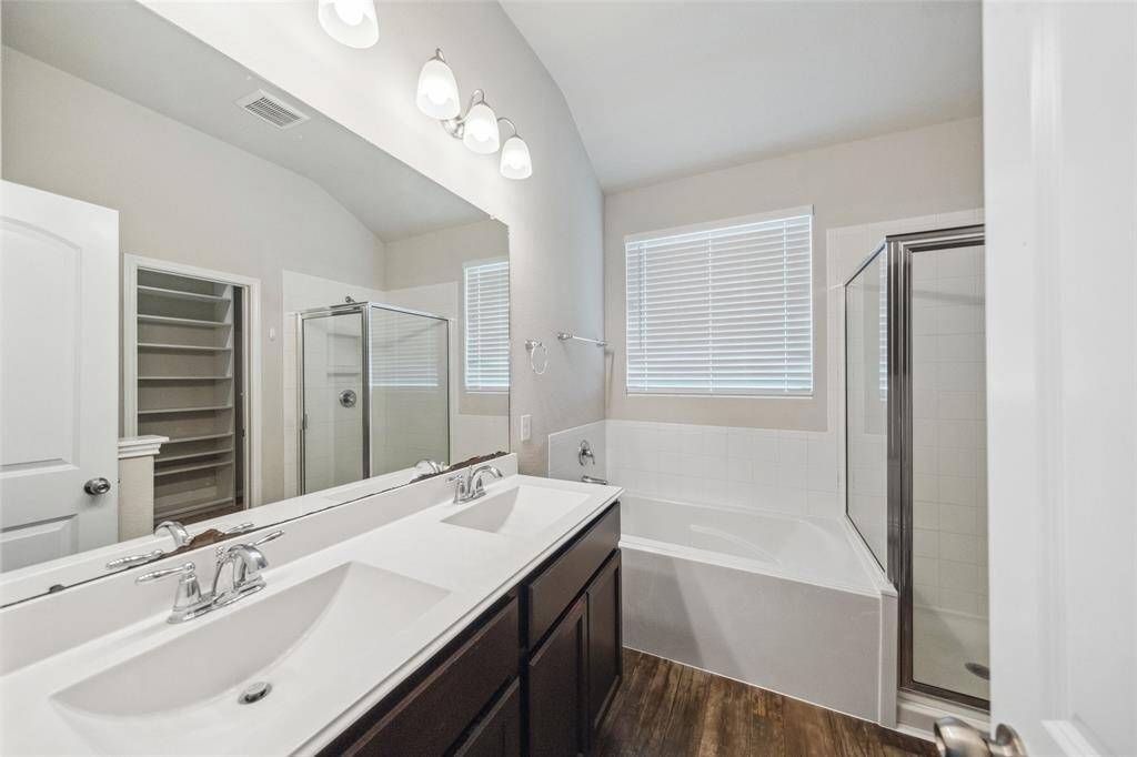 Elegant primary bathroom featuring dual sinks and vanity for storage, a relaxing soaking tub, and a large shower.