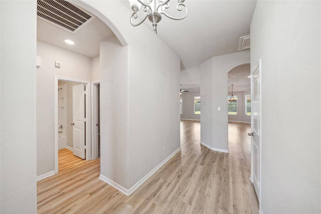 Welcome to a bright, open-concept home featuring an elegant entryway with arched access to secondary bedrooms on the left and seamless flow into the living, kitchen, and dining areas.