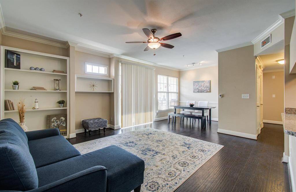 View of living room from front door highlighting a bright and inviting living space with dark wood flooring, built-in shelving, and large windows off the dining area.