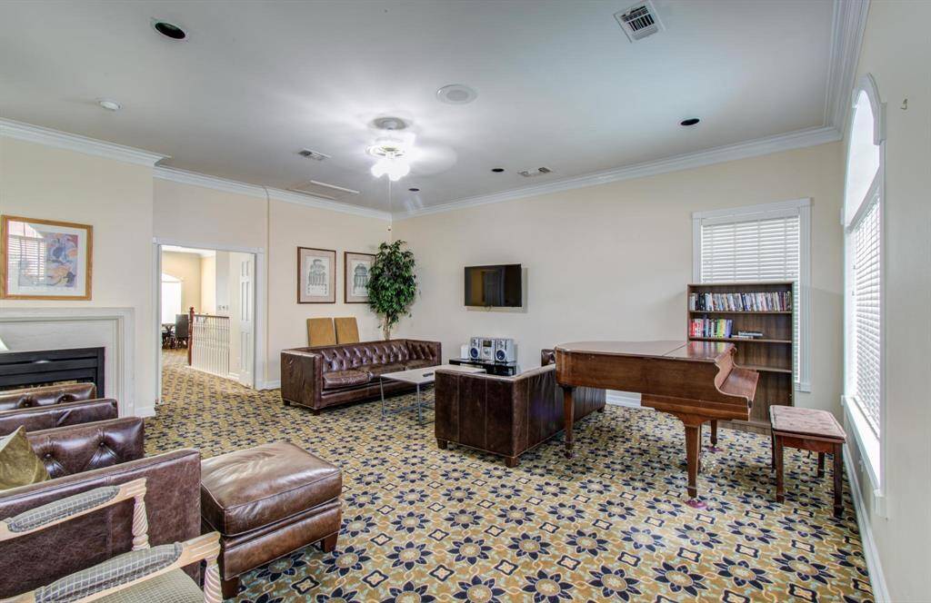 Another view of clubhouse featuring a grand piano, and a cozy fireplace. It has  a built-in entertainment setup, perfect for family gatherings and relaxation.