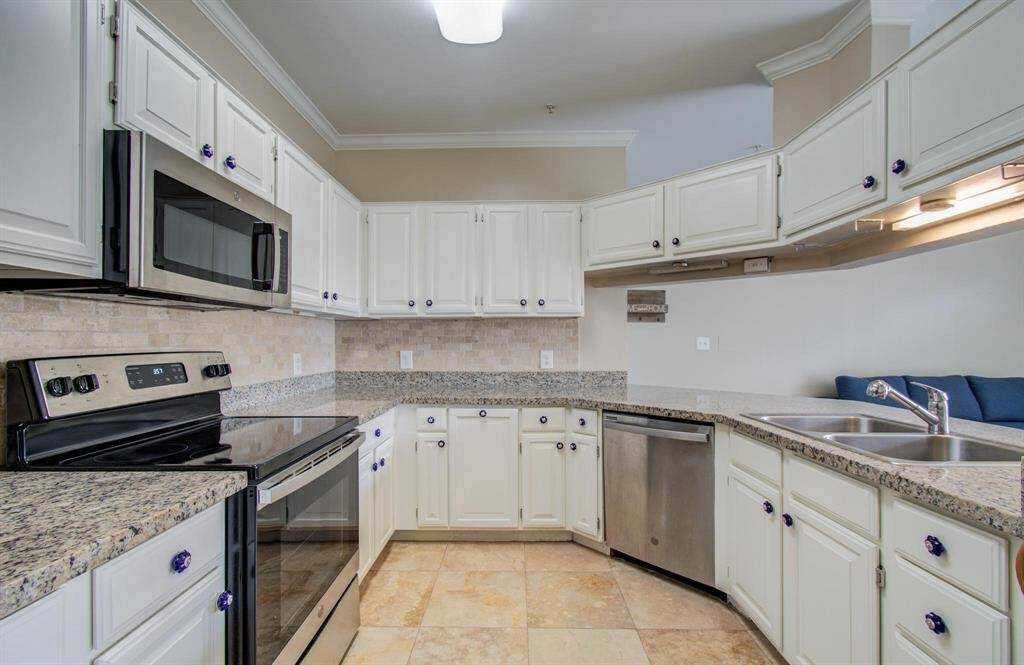Kitchen features modern stainless steel appliances, granite countertops, and white cabinetry offering plenty of storage.