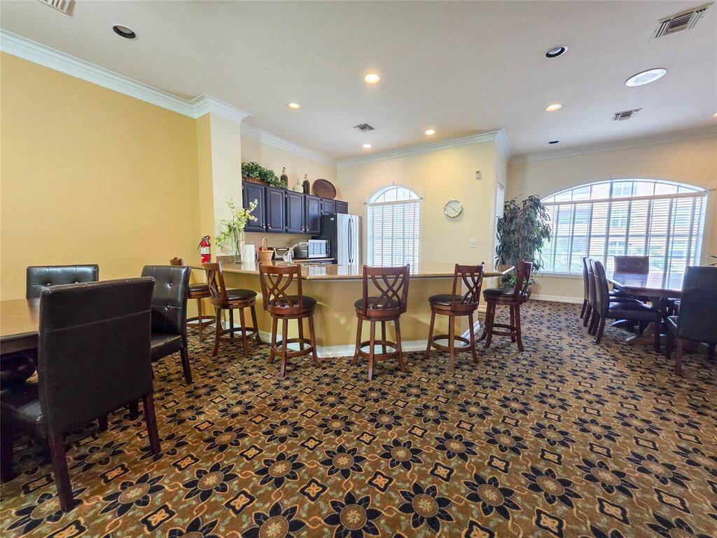 Discover the inviting clubhouse, perfect for gatherings with elegant seating, a functional kitchen, and sunlit windows. Ideal for socializing and relaxation.