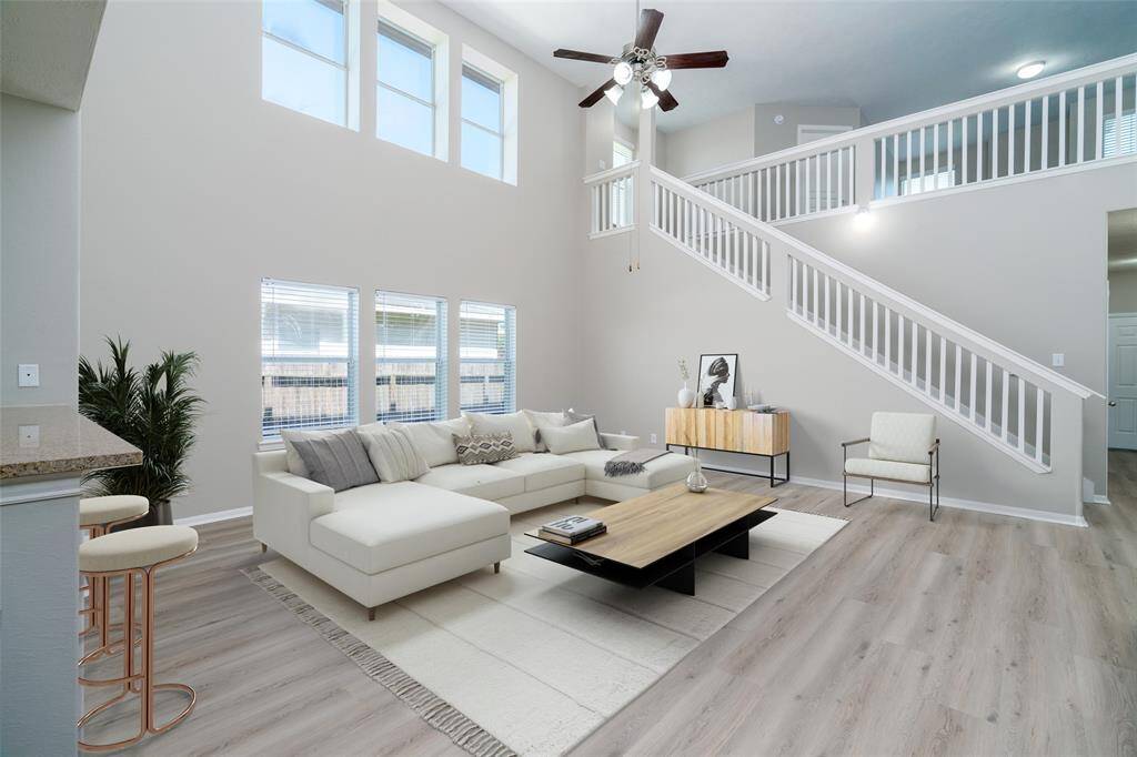 Living room area that includes the open concept layout, high ceilings, and natural light. (virtually staged)