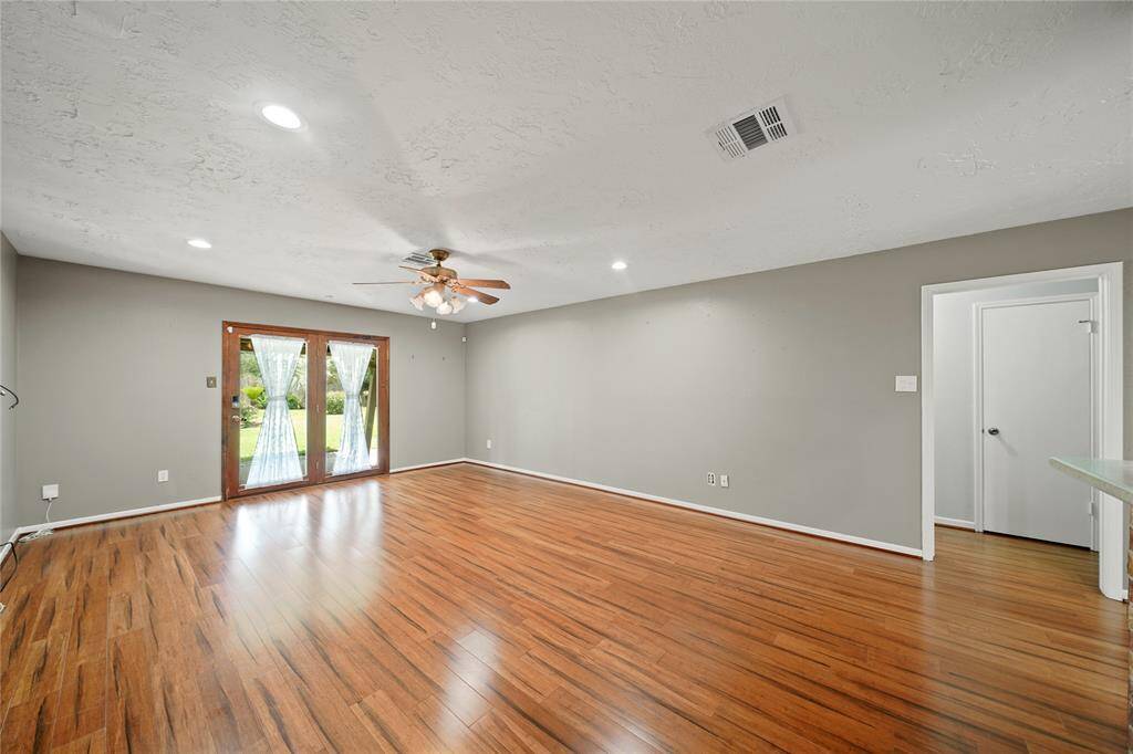 Spacious living area with double doors leading to covered patio. Opening pictured leads to the other two bedrooms and bathroom.