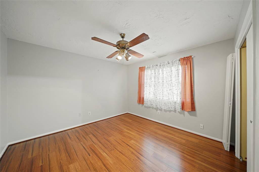 Another bedroom located on the opposite side of the house from primary bedroom,  features wood vinyl plank flooring, a ceiling fan, and a window.