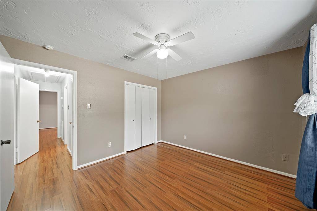 The third bedroom has a closet with white doors and an adjoining hallway  to the other bedroom and bathroom.