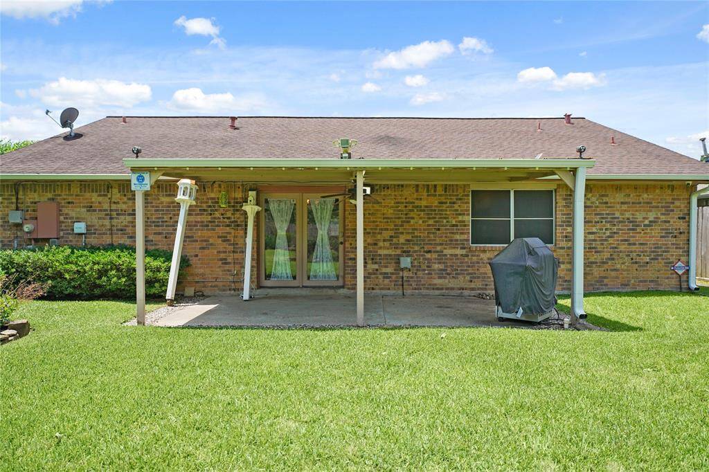 Pictured is the backyard with a covered patio, perfect for outdoor relaxation or entertaining. It features a well-maintained lawn,  providing a cozy and functional outdoor space.