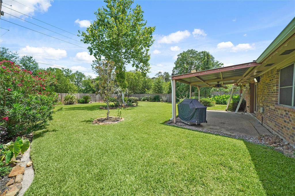 Pictured from the side of the home is shown more of the large, well maintained backyard. This spacious backyard offers endless possibilities, creating a serene outdoor space. A covered patio provides an ideal spot for relaxation and entertaining.