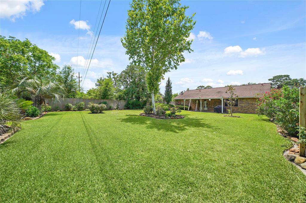 Expansive backyard with well-maintained lawn, mature trees, and landscaped borders, offering ample space for outdoor activities with no back neighbors!