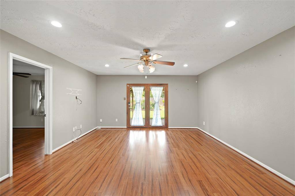 Living area has recessed lighting and double doors that lead to the covered patio and beautiful large backyard. The room opening pictured leads to the primary bedroom.
