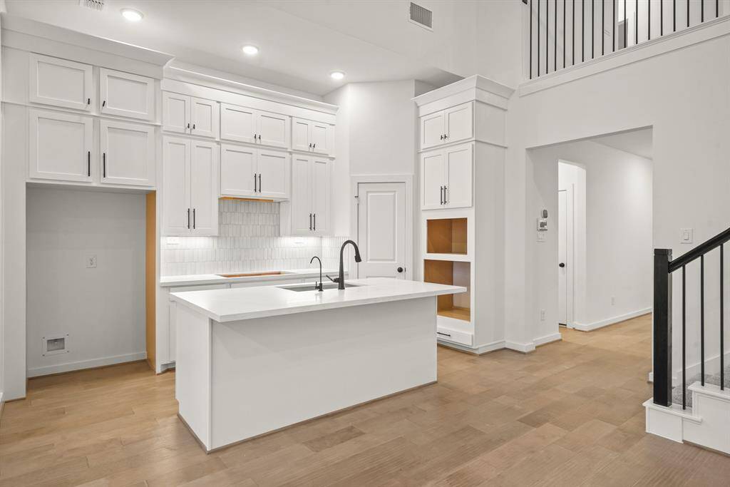 Gorgeous kitchen with top of the line features including quartz countertops, premium stacked cabinetry with 12' ceilings, sleek black hardware, and a farm-style single bowl sink. Stainless steel built-in appliances included along with a fabulous 5-burner cook top and venthood!