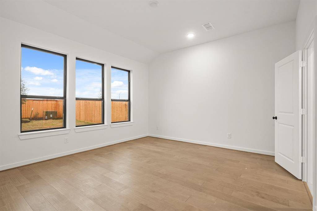 This main bedroom suite is dripping in opulence with hardwood floors and multiple windows.