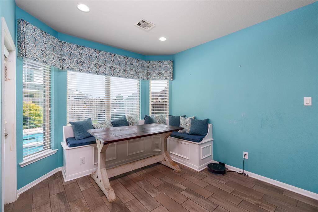 This bright and inviting breakfast area features multiple windows with privacy blinds, recessed lighting, and durable wood-look tile flooring—perfect for enjoying your morning coffee in comfort and style.
