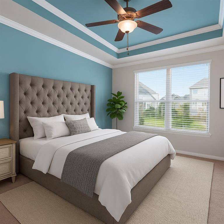 Escape to luxury in the primary suite, showcasing elegant custom paint, a striking tray ceiling, soft carpeting, and a ceiling fan—offering the perfect blend of comfort and style for restful nights and relaxing mornings