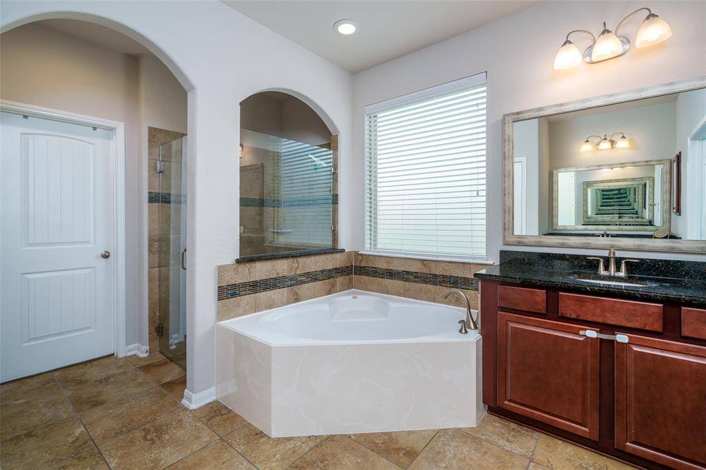 Indulge in spa-like comfort in the primary bathroom, featuring a luxurious soaking bathtub, spacious tiled walk-in shower, and an expansive double sink vanities—perfect for both function and relaxation.