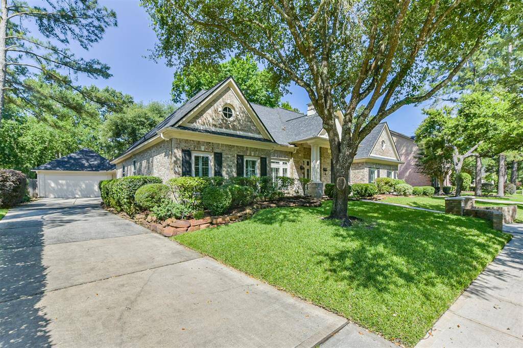 Charming single-story home with a stone facade, lush landscaping, and mature trees. Features a wide driveway leading to a detached garage. Ideal for buyers seeking a serene and inviting exterior.