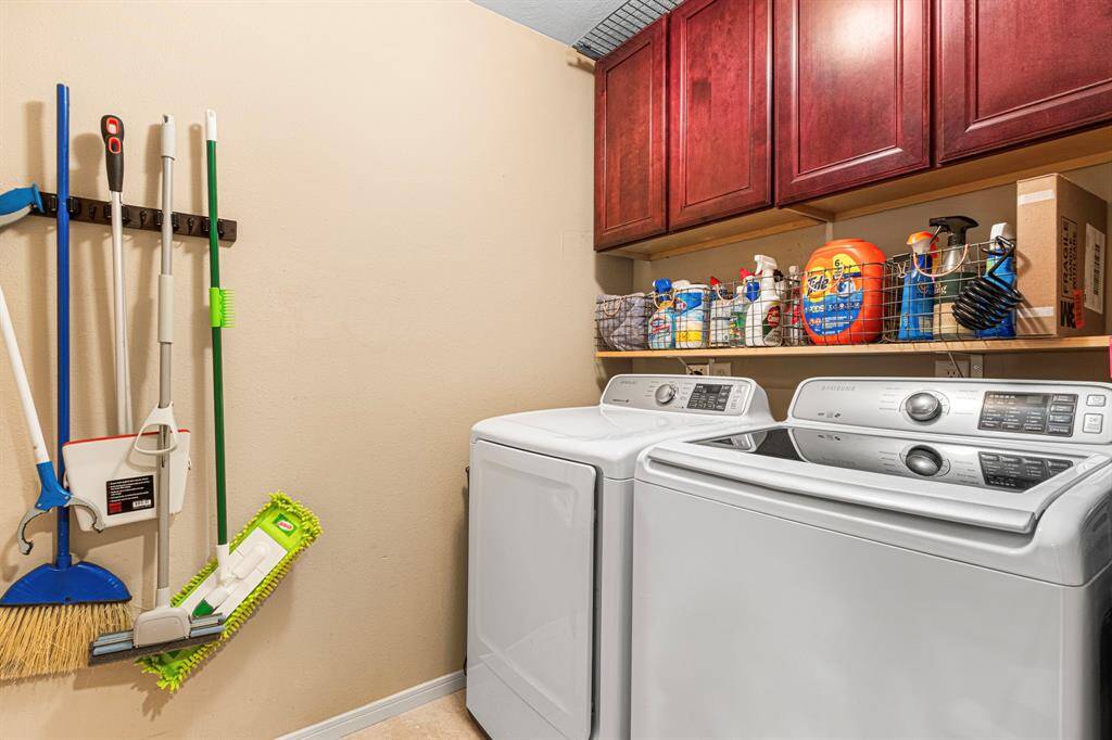This well designed laundry area includes built-in cabinets for detergent and essentials, plus thoughtfully placed hooks to keep cleaning tools organized and off the floor.