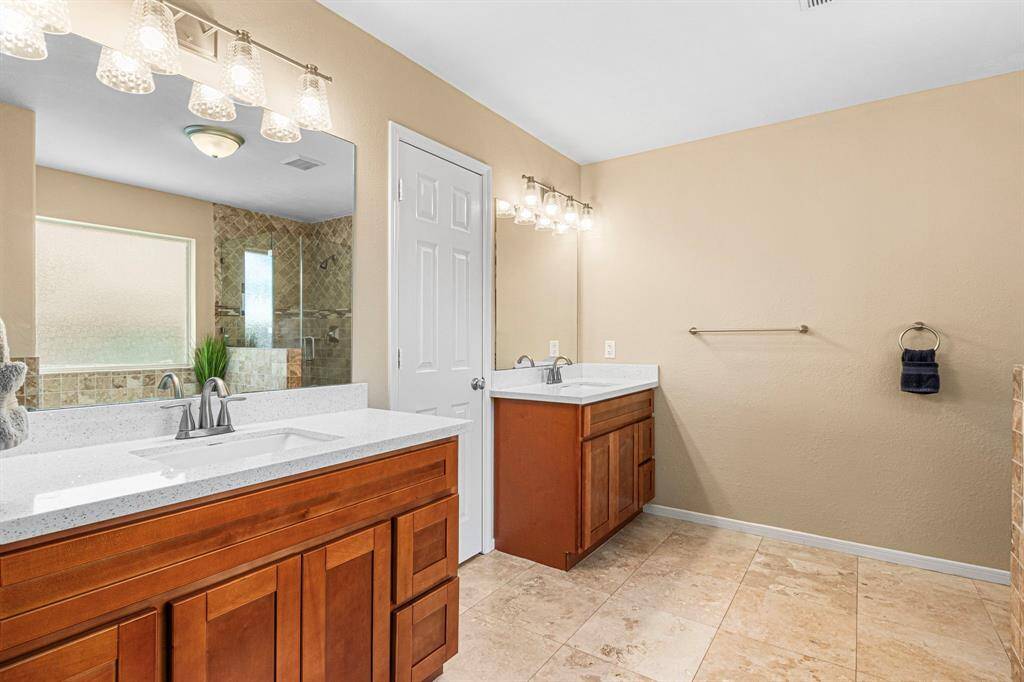 This beautifully appointed master bath offers dual vanities, a separate glass-enclosed shower, and a deep soaking tub-combining function with indulgent relaxation.