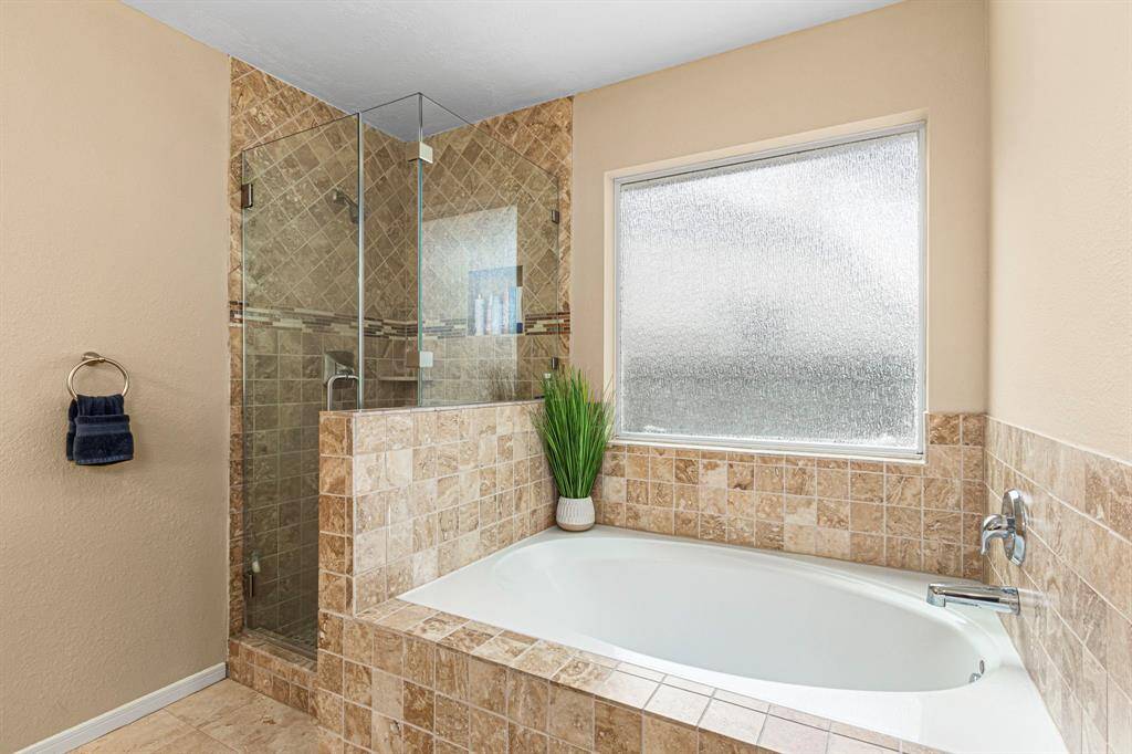 This beautifully appointed master bath offers dual vanities, a separate glass-enclosed shower, and a deep soaking tub-combining function with indulgent relaxation.