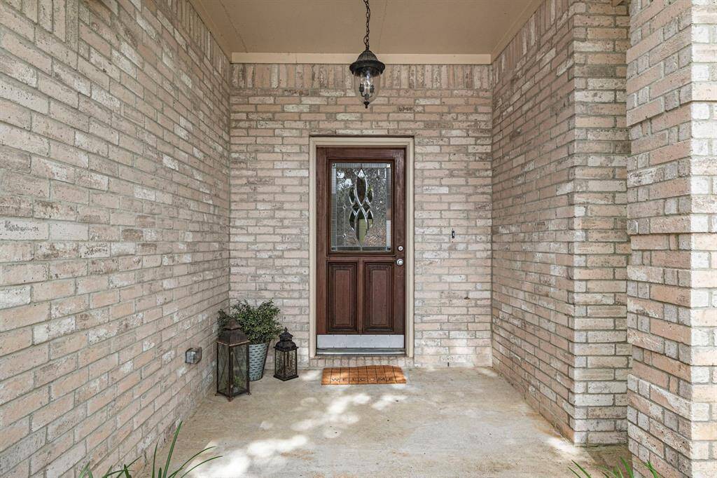 Covered front porch creates welcoming entrance, while the glass-paneled dark wood door floods the foyer w/natural light.