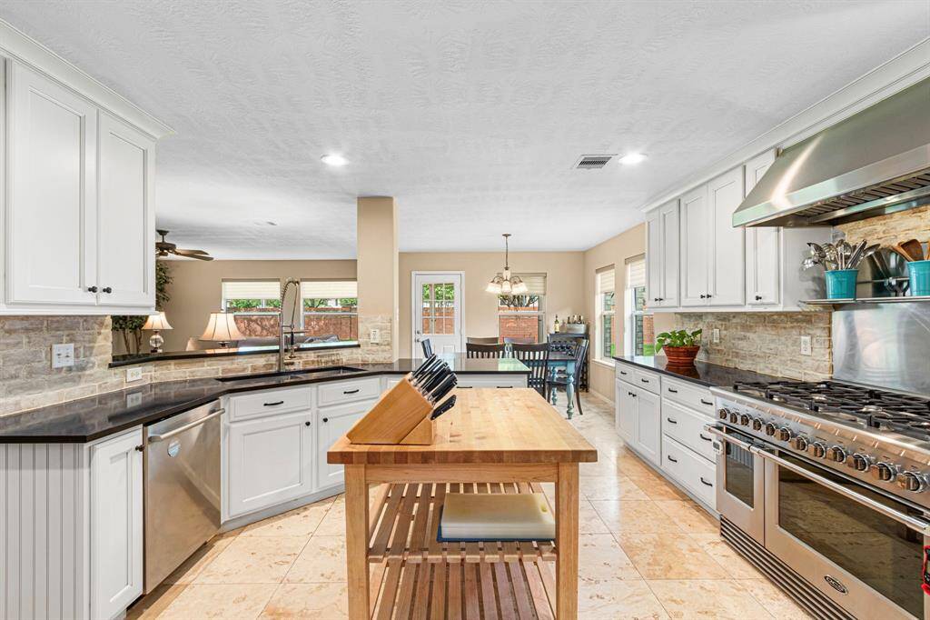 Looking from the kitchen toward the back of the home, a rich woodblock island (conveys with the home!) takes center stage--offering a spacious and durable surface ideal for everyday food prep. Its natural texture adds warmth to the space while enhancing the kitchen's practical layout.