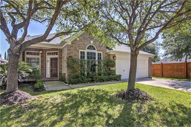 Charming single-story brick home with a welcoming front entrance, surrounded by mature trees and lush landscaping in a cul de sac.