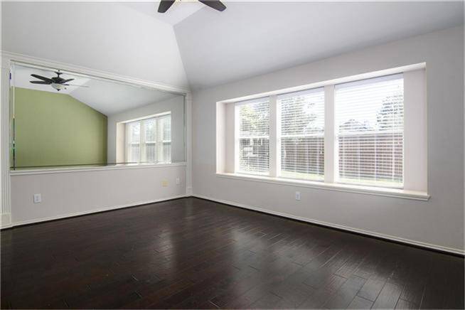 Primary bedroom with wood flooring and natural light.
