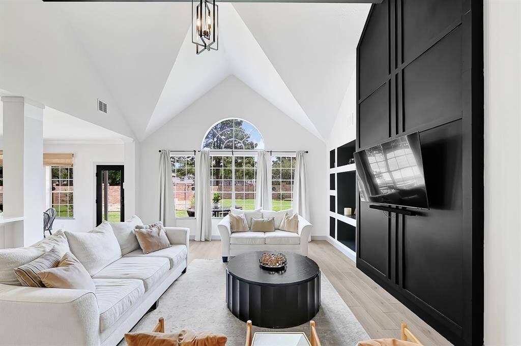The family room impresses with soaring two-story vaulted ceilings and a bold dark accent wall, creating a dramatic yet inviting space.