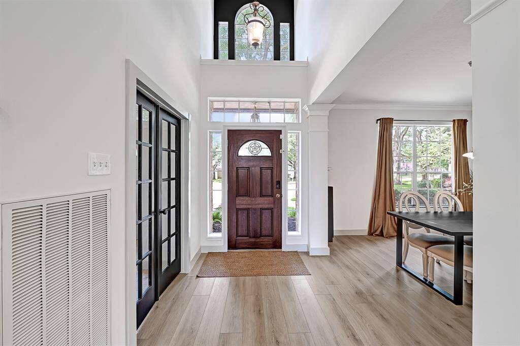 Grand two-story foyer features a welcoming front door and an elegant plant shelf above, setting the tone for the home's spacious design.