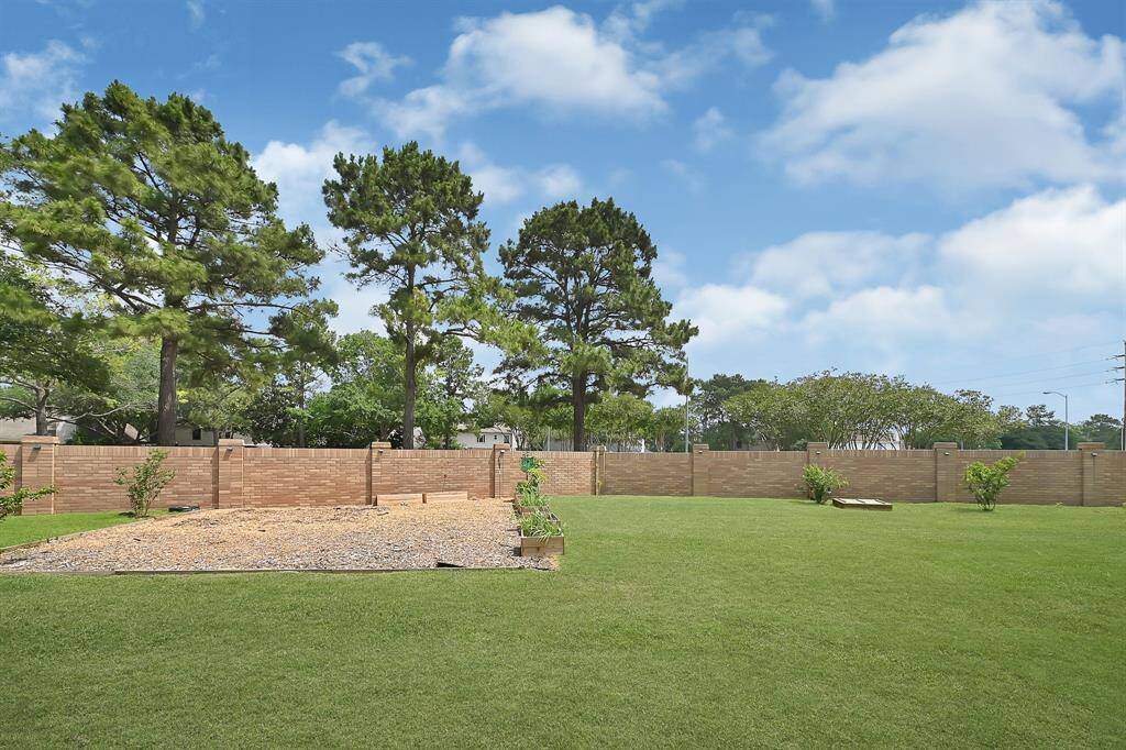 Backyard view highlights a charming garden area and a brick perimeter fence, combining beauty with privacy and function.