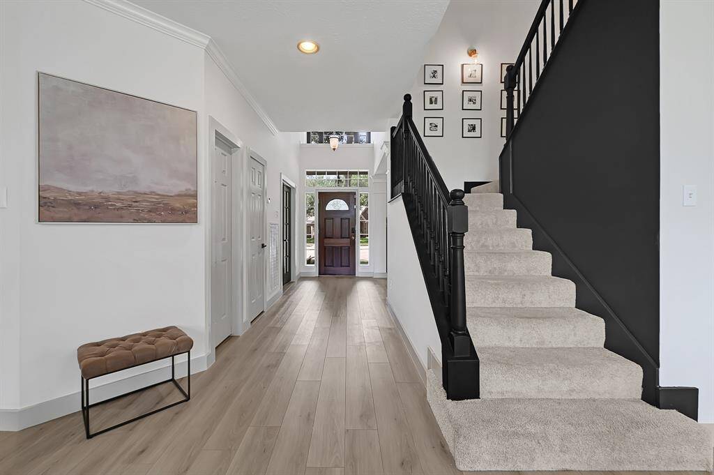 A wider view of the foyer reveals the elegant staircase, complementing the high ceilings and open, airy entryway.