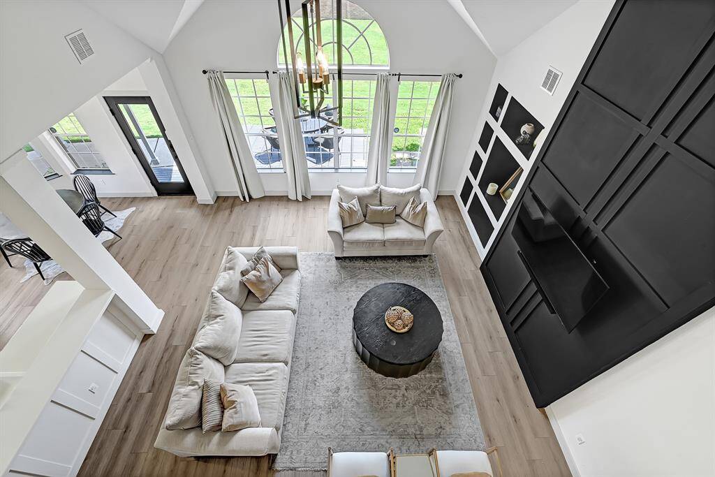View from above showcases the family room with its soaring ceilings, large windows, and striking accent wall.