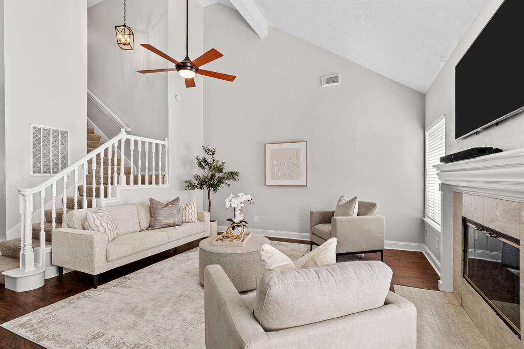 This inviting family room is anchored by a classic tile-surround fireplace and offers plenty of space to relax or entertain beneath vaulted ceilings and a modern ceiling fan.