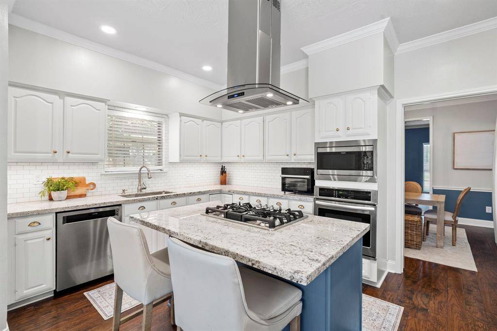 Crisp white cabinetry and a timeless subway tile backsplash give the kitchen a fresh and classic look, with easy access to the formal dining room just beyond.
