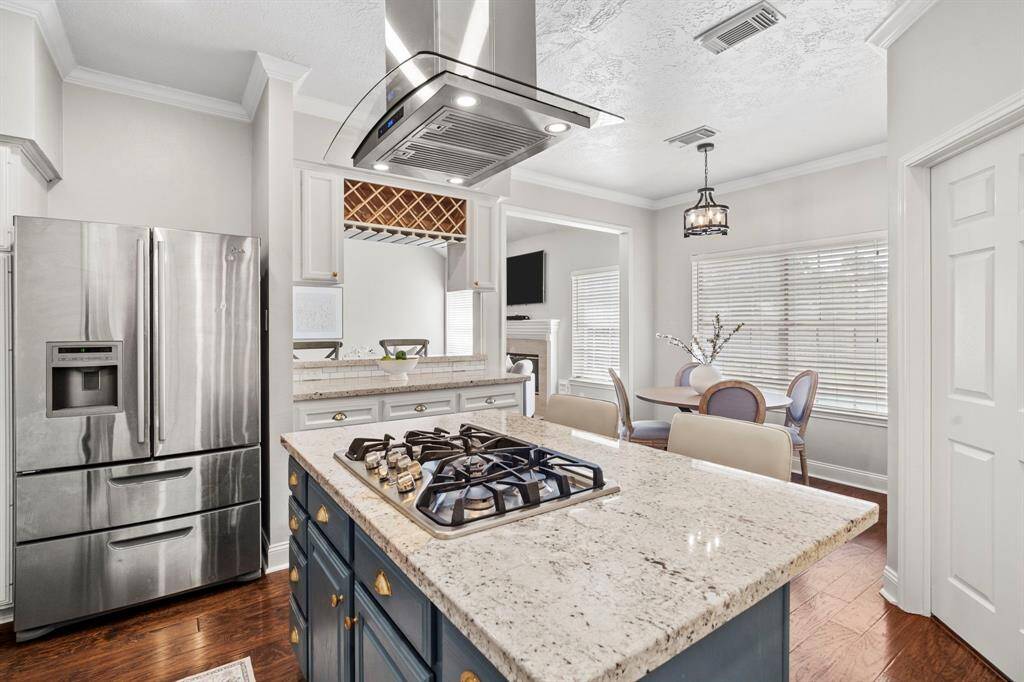 A stainless steel French door refrigerator and a built-in wine rack add both style and functionality, while the open layout connects easily to the family room for entertaining.