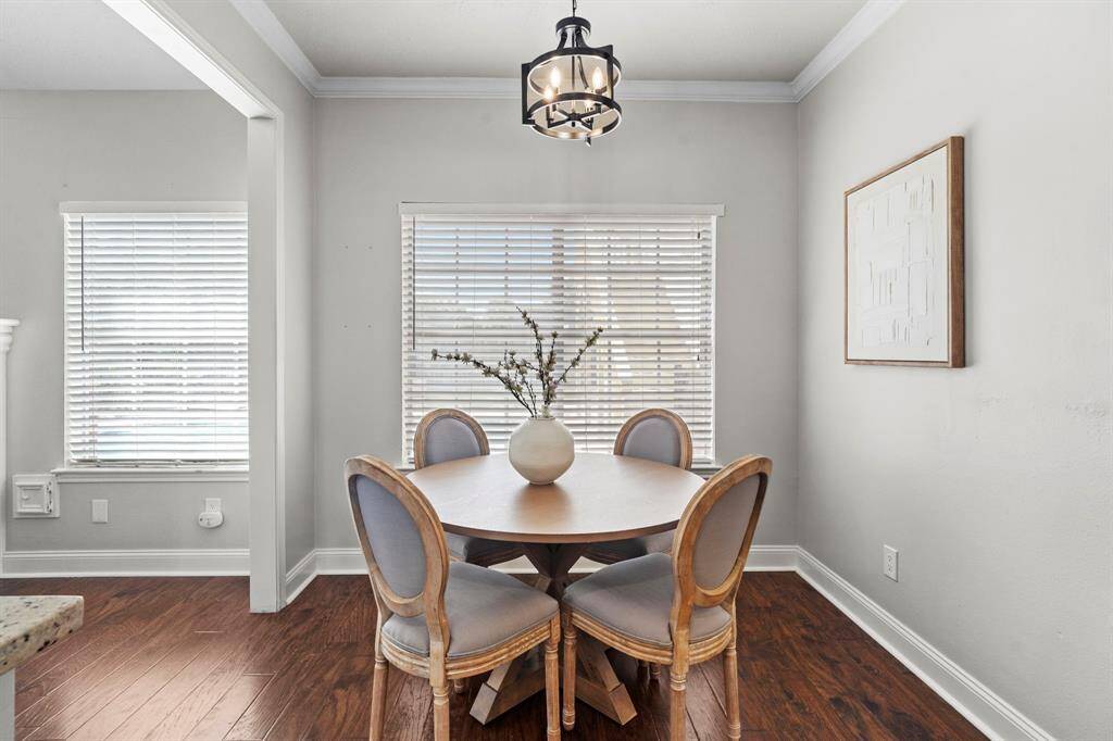 The light-filled dining nook is framed by large windows and features a stylish modern chandelier, creating a cheerful setting for everyday meals.
