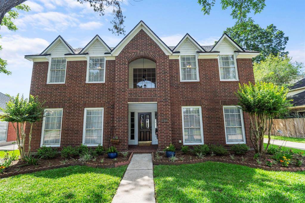 The welcoming front entry features a covered porch, elegant brick detailing, and an arched balcony above that adds architectural charm to the home’s exterior.