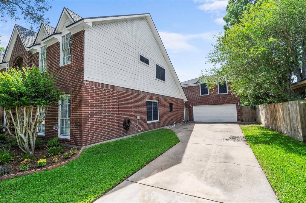 A long driveway leads to a detached two-car garage, providing ample off-street parking and easy access to the spacious backyard.