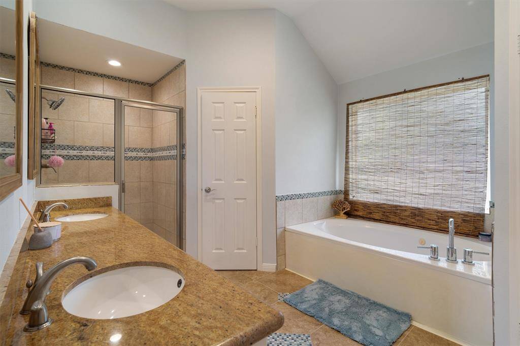 Primary en suite with double sinks, fully tiled standalone shower, and separate garden tub