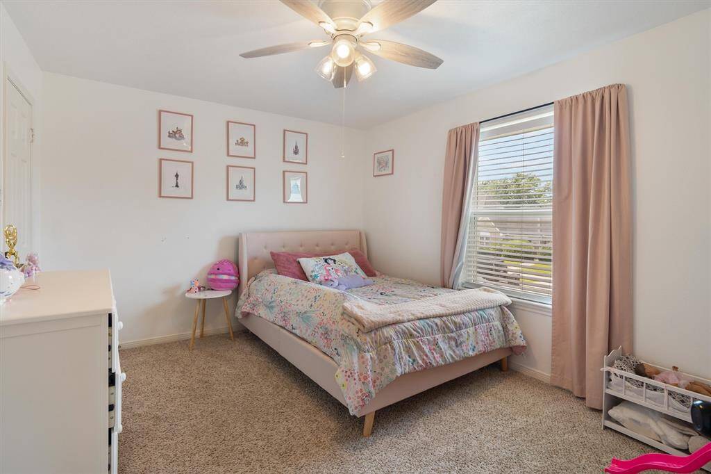 Second bedroom with ceiling fan and window overlooking the front yard.